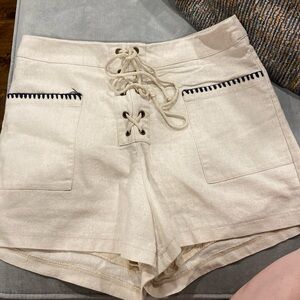 Tan colored shorts with black stitching on pockets